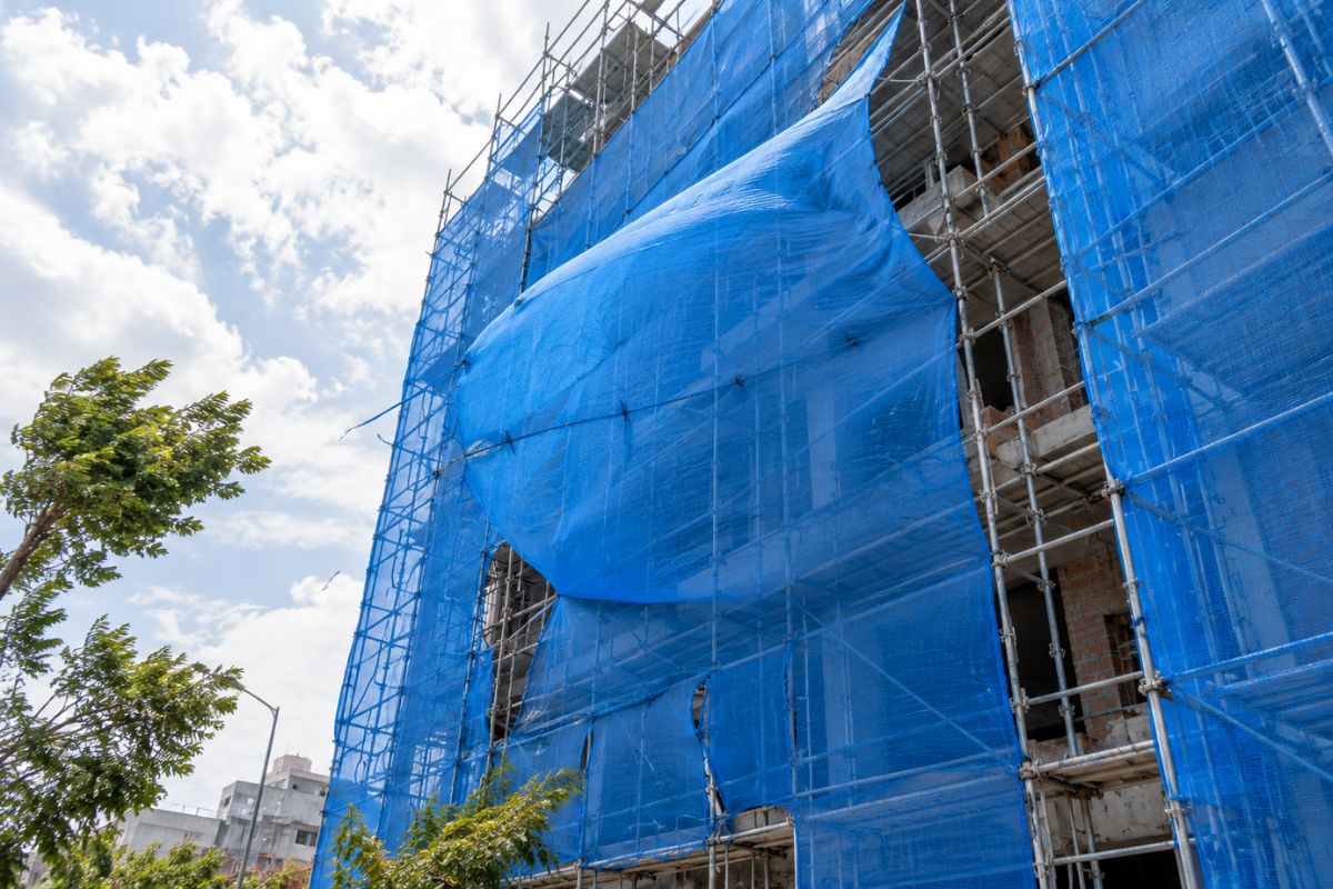 Lưới bao che bị gió thổi phồng như cánh buồm trên giàn giáo