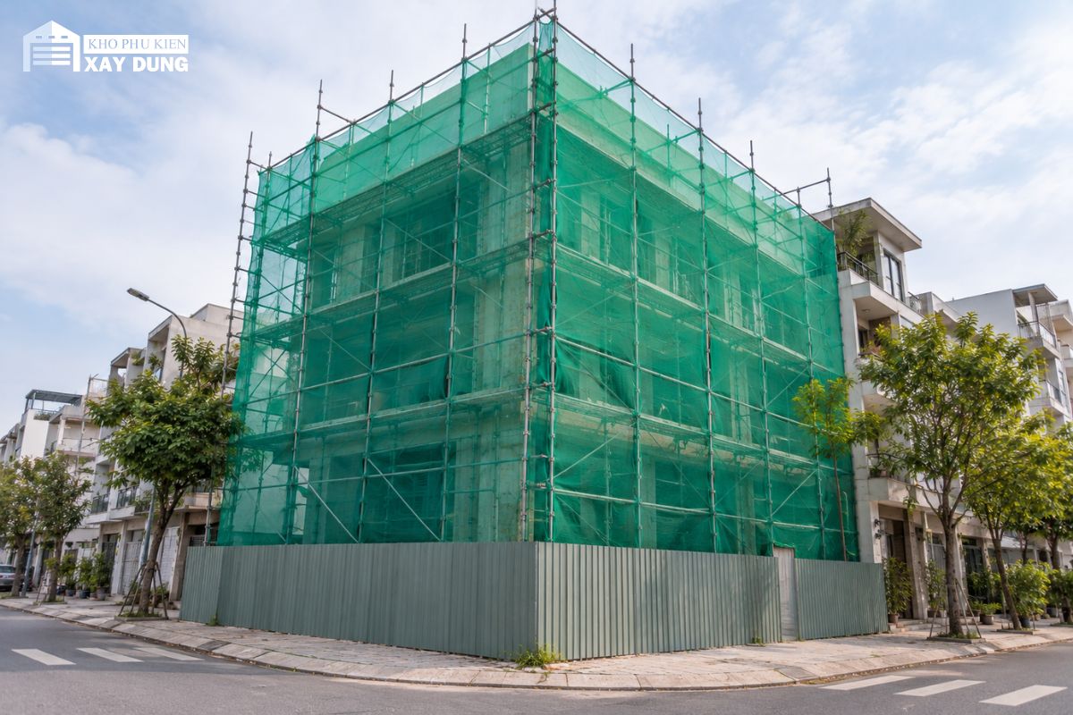 Nhà phố góc đường được phủ lưới bao che trên hai mặt giàn giáo